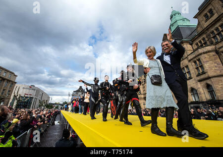 Recklinghausen, Deutschland. 04 Mai, 2019. Die Bürger der Stadt Recklinghausen, einschließlich eines frisch verheirateten Paar und eine Gruppe von Tauchern, zu Fuß über einen Laufsteg auf dem Rathausplatz. In einer Mischung aus Installation, Konzert und Theater, gut über 100 ausgewählte Bürger präsentierten sich und ihre Lebensgeschichten durch Musik, großformatige Bilder und kurze Texte auf zwei großen Bildschirmen an der Ruhrfestspiele unter dem Motto: "Was ist die Stadt aber die Menschen begleitet? Quelle: Bernd Thissen/dpa/Alamy leben Nachrichten Stockfoto