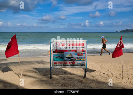 Zu Beginn der Regenzeit, rote Fahnen und ein Warnzeichen in Patong Beach, Phuket, Thailand, drängen die Besucher nicht zu schwimmen. Stockfoto