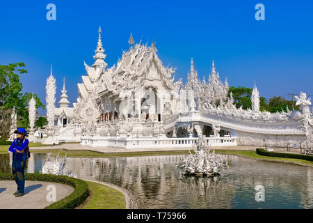 Ein Besucher posieren vor Wat Rong Khun, dem so genannten weißen Tempel in Chiang Rai, Thailand, entworfen vom Künstler Chalermchai Kositpipat Stockfoto