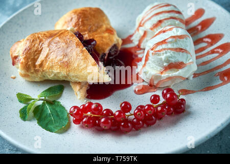 In Scheiben geschnittene Hausgemachte berry Strudel mit frischen rote Johannisbeere Beeren und Puderzucker auf einem alten Hintergrund auf einer Platte mit Eis pic serviert. Stockfoto