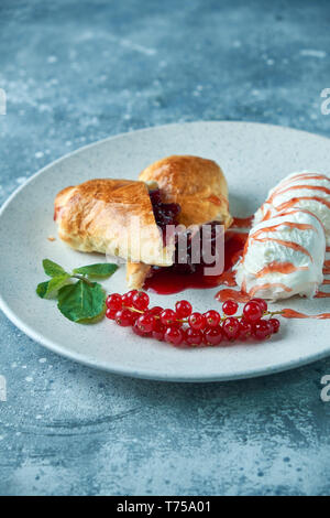 In Scheiben geschnittene Hausgemachte berry Strudel mit frischen rote Johannisbeere Beeren und Puderzucker auf einem alten Hintergrund auf einer Platte mit Eis pic serviert. Stockfoto