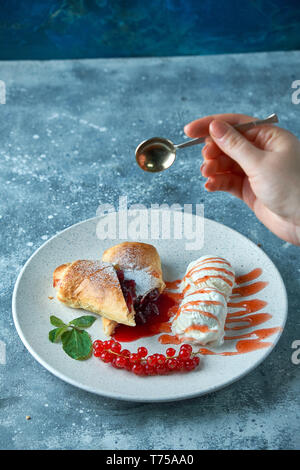 In Scheiben geschnittene Hausgemachte berry Strudel mit frischen rote Johannisbeere Beeren und Puderzucker auf einem alten Hintergrund auf einer Platte mit Eis pic serviert. Stockfoto