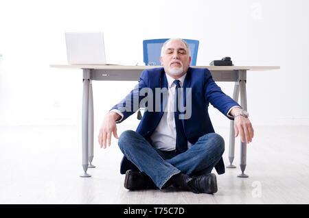 Alter Geschäftsmann Yoga Übungen im Büro Stockfoto