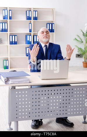 Alter Geschäftsmann Yoga Übungen im Büro Stockfoto