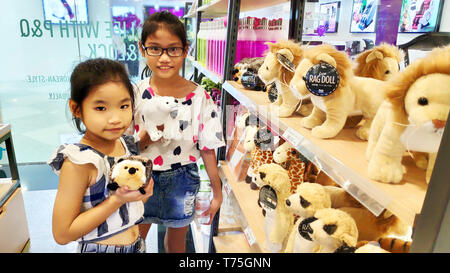 Zwei süße Vietnamesischen asiatische Mädchen lächelnd auswählen Braun lions Material Tiere auf Regal für Geburtstag Geschenk im Supermarkt Stockfoto