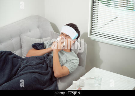 Menschen frieren, liegend auf dem Sofa und seine Nase weht Stockfoto