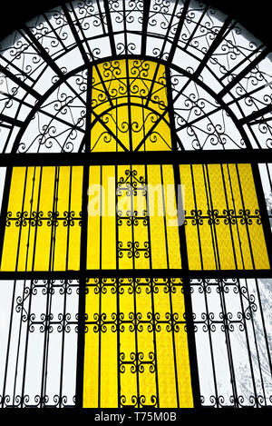 Licht durch eine gelb gefärbte Kreuzes Fenster aus buntem Glas und Metall Werke der Kirche in Leon Stadt scheint, Provinz Iloilo, Philippinen Stockfoto