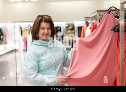 Die Frau entscheidet, Kleidung im Store. Stockfoto