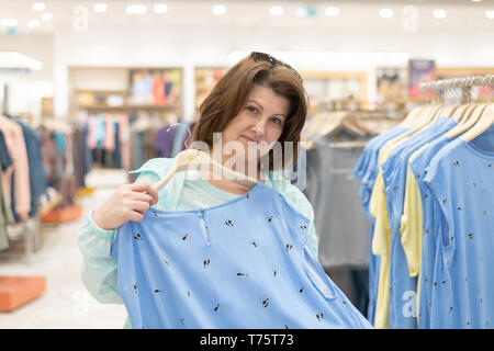 Die Frau entscheidet, Kleidung im Store. Stockfoto