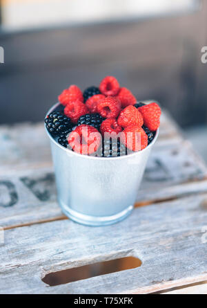 Detailansicht von saftigen und gesund Himbeeren und Brombeeren in einen metallischen Schale mit Holz- Hintergrund. Gesunde und frische Snacks und Frühstück. Ve Stockfoto