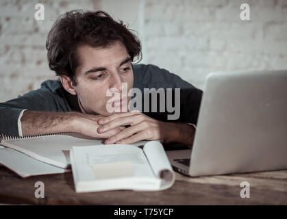 Überarbeitet und müde männliche Kursteilnehmer spät in der Nacht arbeiten am Laptop versuchen nicht zu schlafen Gefühl ermüdet, besorgt und traurig. Moody Dark Light. Endg. Stockfoto
