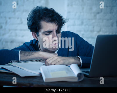 Überarbeitet und müde männliche Kursteilnehmer spät in der Nacht arbeiten am Laptop versuchen nicht zu schlafen Gefühl ermüdet, besorgt und traurig. Moody Dark Light. Endg. Stockfoto