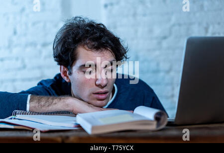 Überarbeitet und müde männliche Kursteilnehmer spät in der Nacht arbeiten am Laptop versuchen nicht zu schlafen Gefühl ermüdet, besorgt und traurig. Moody Dark Light. Endg. Stockfoto