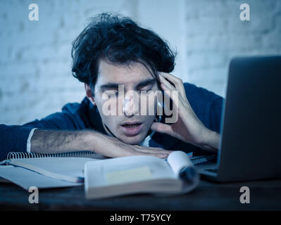 Überarbeitet und müde männliche Kursteilnehmer spät in der Nacht arbeiten am Laptop versuchen nicht zu schlafen Gefühl ermüdet, besorgt und traurig. Moody Dark Light. Endg. Stockfoto