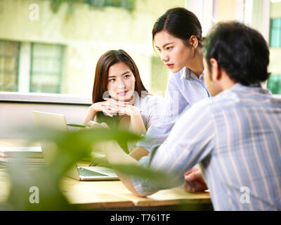 Drei asiatische junge Unternehmer treffen im Büro, den Schwerpunkt auf die Person auf der linken Seite. Stockfoto