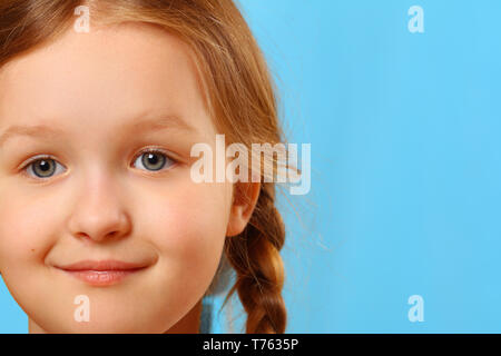 Closeup Portrait einer niedlichen kleinen Kind Mädchen auf einem blauen Hintergrund. Stockfoto