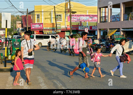 Leon, Provinz Iloilo, Philippinen - April 18, 2019: Junge Eltern mit ihren Kindern zu Fuß auf den Straßen während der Nachmittag der Verkehr Stockfoto