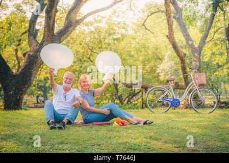Ältere Paare lesen Zeitung im Garten bei Sonnenuntergang. Konzept paar Elder lieben. Stockfoto