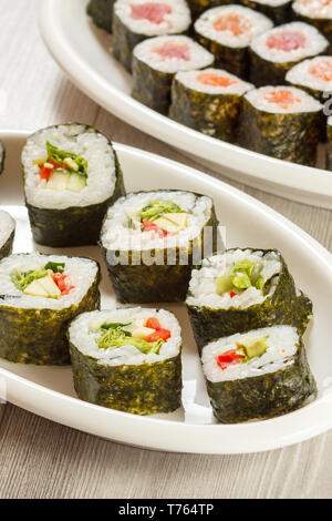 Verschiedene sushi Rollen mit Reis und Algen Blätter auf keramischen Platten. Ansicht von oben. Stockfoto
