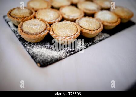 Schließen Sie köstliche hausgemachte saisonale frosted Weihnachten Mince Pies auf schiefer Platte auf ein Buffet in einem Luxushotel. Stockfoto