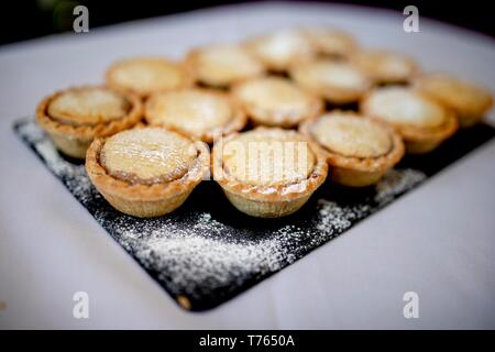 Schließen Sie köstliche hausgemachte saisonale frosted Weihnachten Mince Pies auf schiefer Platte auf ein Buffet in einem Luxushotel. Stockfoto