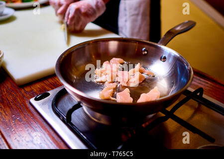 Heiße Pfanne mit Fleisch auf dem Herd. Ein Koch bereitet Teller auf Küche des Restaurant oder Hotel. Stockfoto