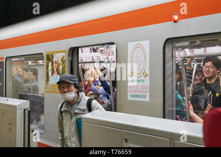 Ein erwachsener japanischen Mann mit einem Mundschutz disembarks aus einem Zug Auto auf dem Tsukuba Express am Bahnhof in Asakusa, Tokyo, Japan. Stockfoto