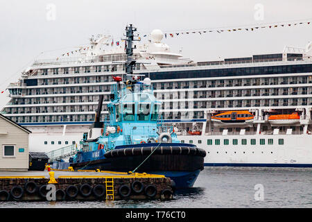 Tug Boat Vivax an tollboden Quay. Im Hintergrund, Kreuzfahrtschiff Viking Meer, skolten Terminal im Hafen von Bergen, Norwegen. Einen grauen, regnerischen Tag im April. Stockfoto