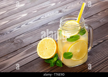 Frische Limonade im Marmeladenglas mit Stroh auf einem Holztisch Stockfoto