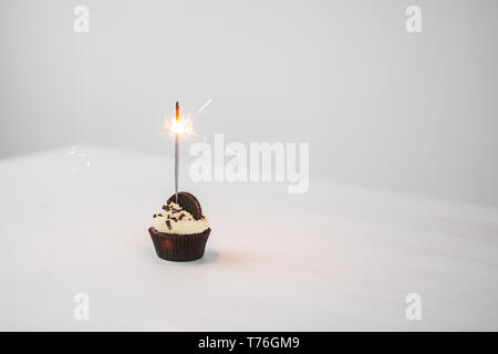 Essen und Urlaub Konzept - Geburtstag Cupcake mit Wunderkerzen auf weißem Hintergrund mit Kopie Raum Stockfoto
