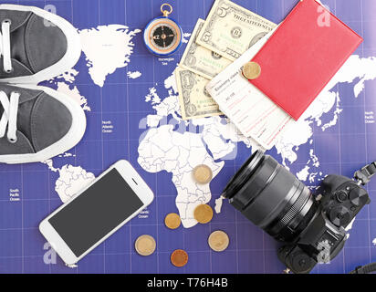 Foto Kamera, Reisepass, Schuhe, Handy und Geld auf der Weltkarte. Reiseplanung Konzept Stockfoto