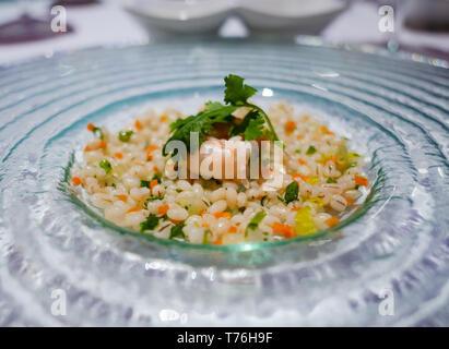 Kleine portion Risotto mit Garnelen und ein Blatt Petersilie. Flache Tiefenschärfe mit der Garnele im Fokus. Stockfoto