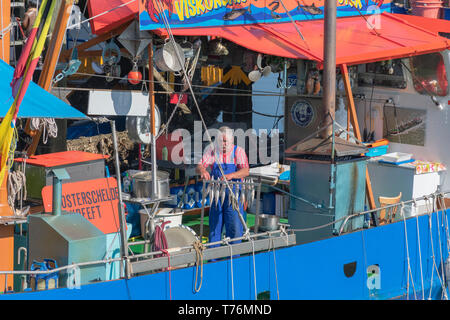 Breskens, Niederlande, 21. April 2019 Fischerboot Die glücklichen Hummer. Sprotte, Makrele und Aal sind auf diesem Boot geraucht. Der Mensch hängt, Makrelen zu rauchen Stockfoto