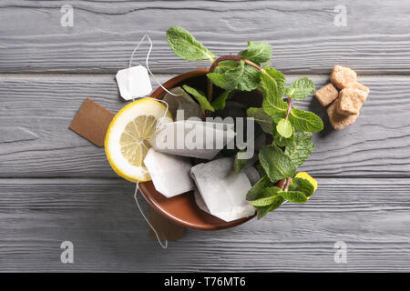 Schüssel mit Teebeuteln und Minze auf hölzernen Tisch Stockfoto