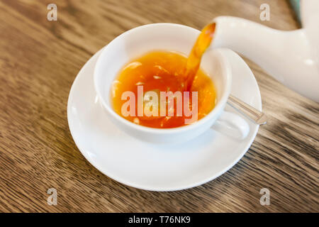 Erhöhte Nahaufnahme der Eingabe von frischem Tee in einem weißen Teetasse. Stockfoto