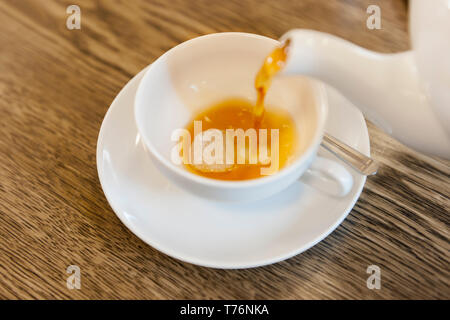 Erhöhte Nahaufnahme der Eingabe von frischem Tee in einem weißen Teetasse. Stockfoto