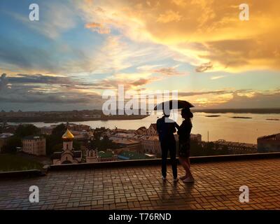 Ein paar unter einem Sonnenschirm Sonnenuntergang an der Einmündung der Oka und Wolga Flüssen in Nischni Nowgorod Stockfoto