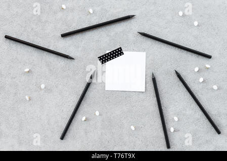 Leerer Hinweis Papier und scharfe schwarze Bleistifte auf grauem Beton Hintergrund. Stockfoto