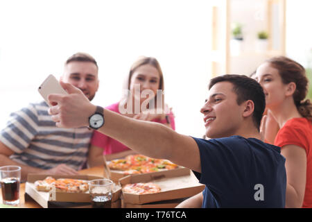 Junge Menschen mit Pizza unter selfie im Innenbereich Stockfoto