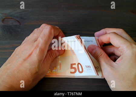 Closeup Mann Hände zählen 50 Euro-banknoten auf dunklen Holztisch Stockfoto