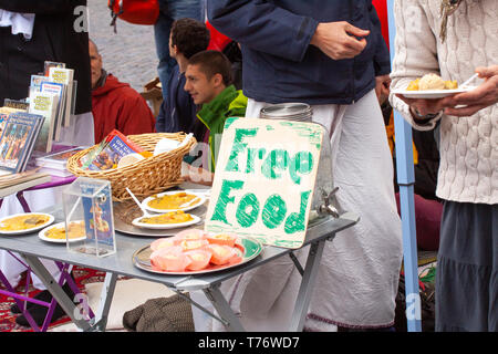 Hare Krishna Mitglieder singen und spielen auf der Straße mit Vorzeichen bietet kostenloses Essen. Stockfoto