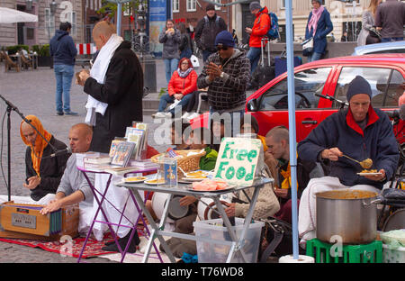 Hare Krishna Mitglieder singen und spielen in der streetwith Zeichen bietet kostenfreies Essen Stockfoto