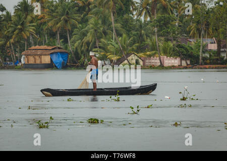 Man steht auf langen einbaum in den Untiefen der Jungle River ziehen in einem Fischernetz mit nativen Gehäuse im Hintergrund Stockfoto