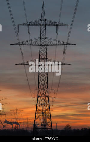 Silhouette von Hochspannungsleitungen und Pylonen, die zu einem dampfkraftwerk vor einem bunten nach Sonnenuntergang Himmel. Karlsruhe, Deutschland Stockfoto