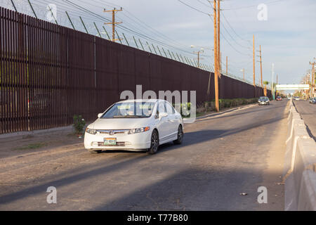 MEXICALI, MEXIKO - 8 April ein Auto fährt von der US-mexikanischen Grenze Mauer April 8, 2019 in Mexicali, Mexiko. Unter den Gebäuden des Zentrums von Mexicali Stockfoto