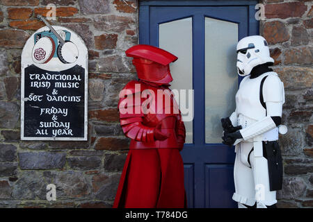 Mitglieder der "501st Legion Irland Garnison' gekleidet als Prätorianergarde (links) und ein Stormtrooper auf den Straßen von Portmagee, Kerry, während der Mai der 4. Festival, wo Szenen aus Star Wars gedreht wurden. Stockfoto