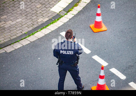 ESSEN/Deutschland - VOM 29. APRIL 2019: Polizei Mann auf walkie-talkie kommunizieren. Stockfoto