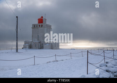 Panoramabild der Leuchtturm am Kap Dyrholaey mit Schnee und am frühen Morgen Licht, Winter in Island Stockfoto