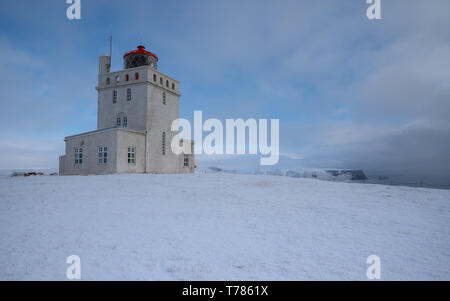 Panoramabild der Leuchtturm am Kap Dyrholaey mit Schnee und am frühen Morgen Licht, Winter in Island Stockfoto