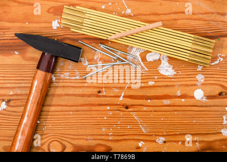 Hammer, Zollstock und Nägel auf eine gefleckte Holz. Stockfoto